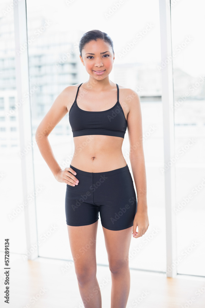 Content dark haired model in sportswear posing with a hand on th