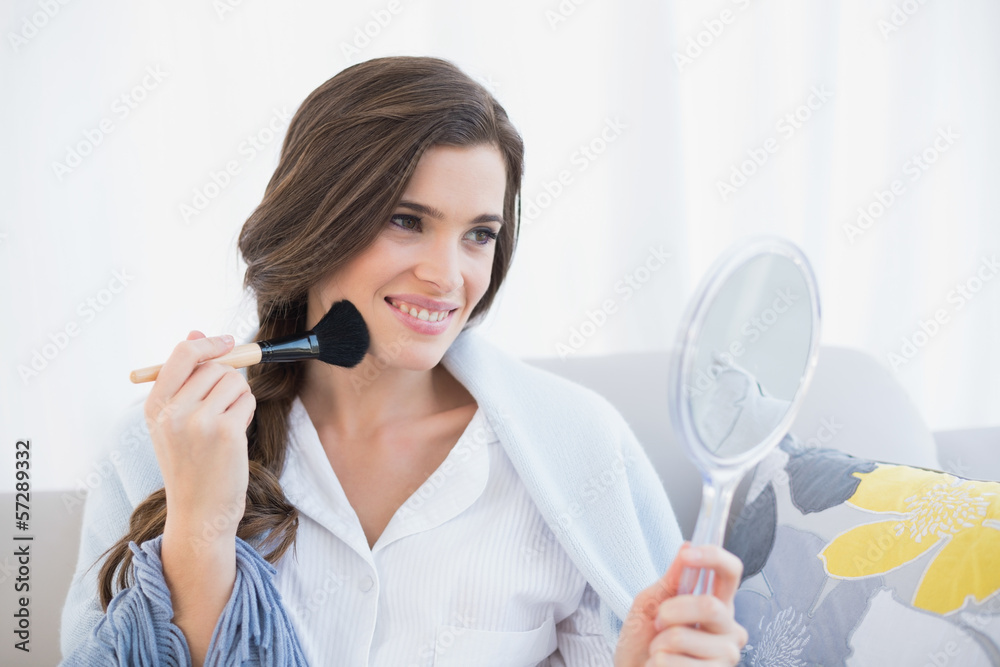 Cheerful casual brown haired woman in white pajamas applying pow Cheerful casual brown haired woman in white pajamas applying pow