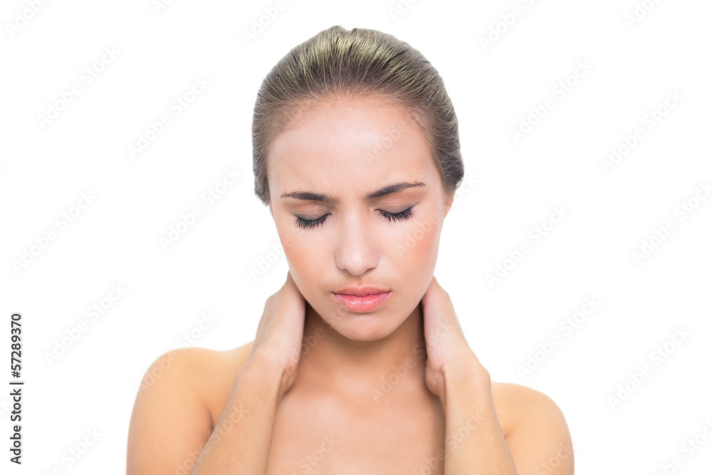 Frowning young brunette woman suffering from sore neck Frowning young brunette woman suffering from sore neck