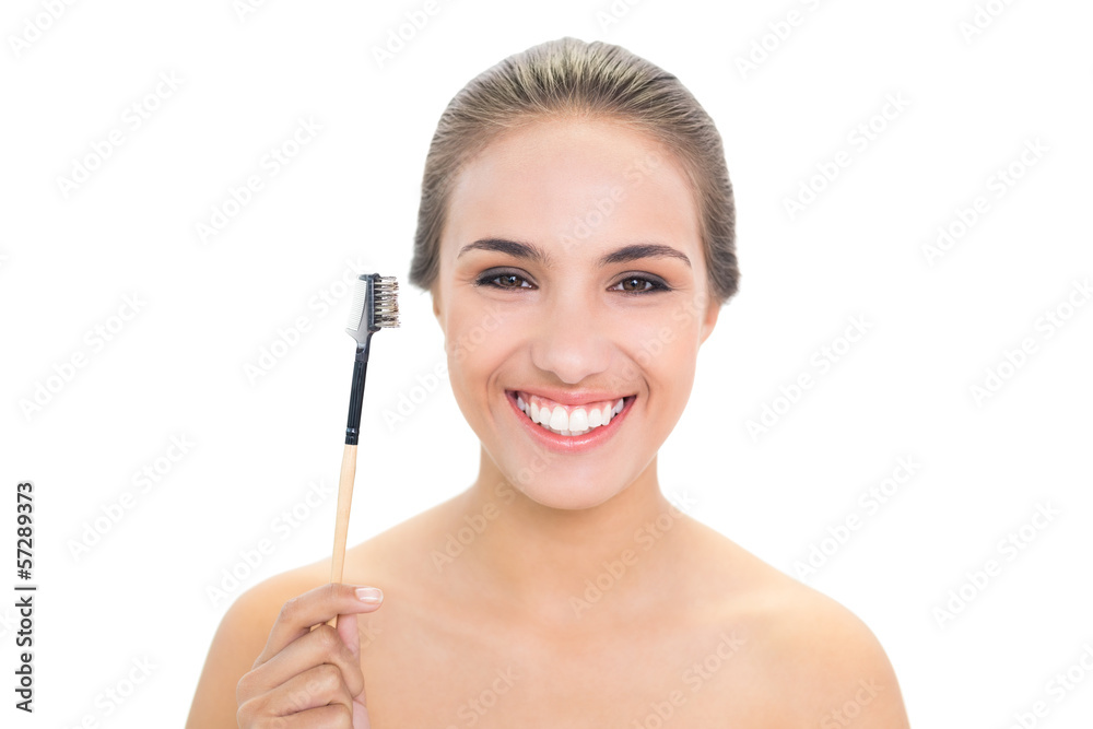 Smiling young brunette woman holding eyebrow brush