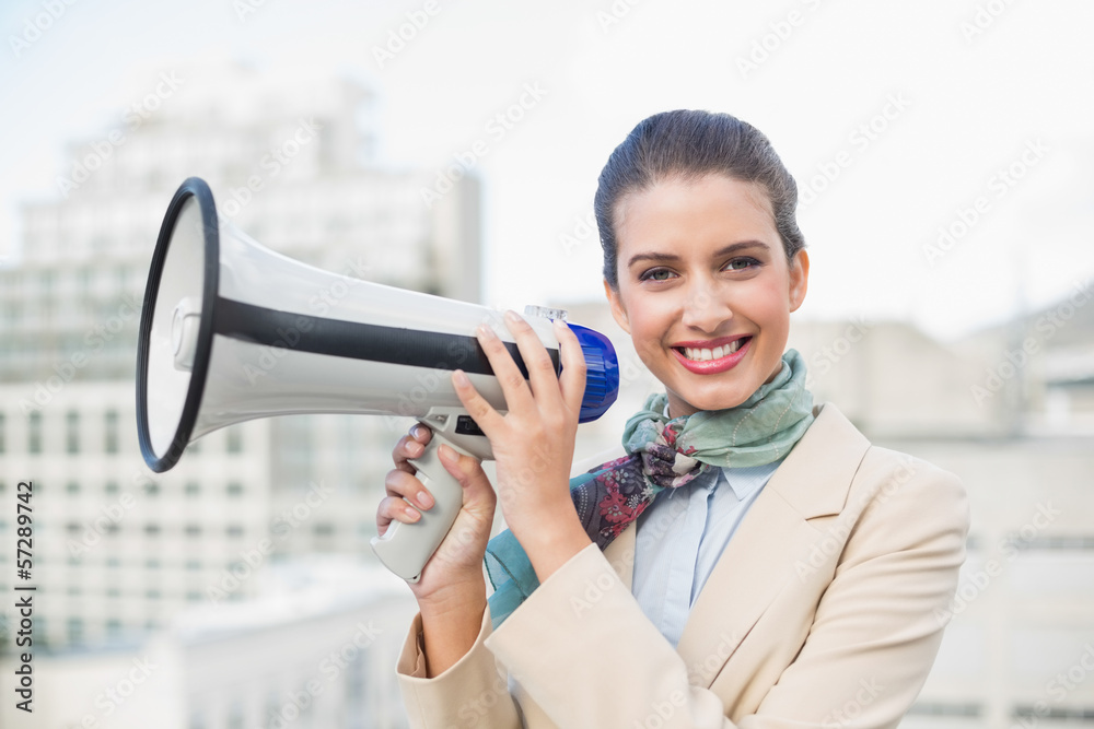 Happy smart brown haired businesswoman holding a megaphone Happy smart brown haired businesswoman holding a megaphone
