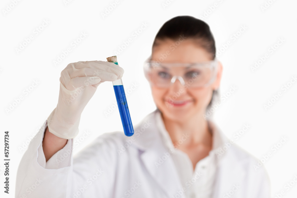 Female scientist looking at a blue test tube Female scientist looking at a blue test tube