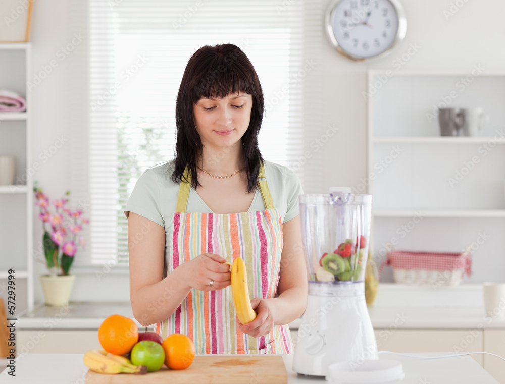 Good looking brunette woman pealing a banana while standing Good looking brunette woman pealing a banana while standing
