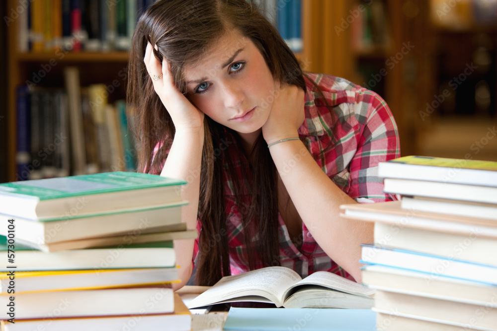 Depressed student surrounded by books Depressed student surrounded by books