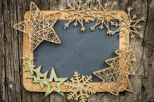 Gold Christmas tree decorations on vintage wooden blackboard