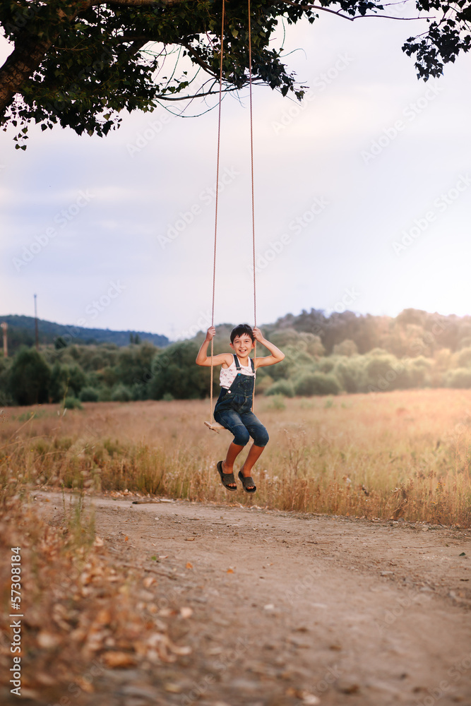 Obraz premium Happy young boy playing on swing in a park