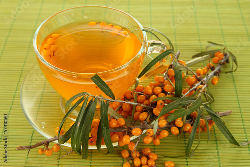 Branches of sea buckthorn with tea on bamboo background photo