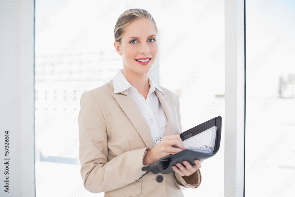 Smiling blonde businesswoman writing on datebook Smiling blonde businesswoman writing on datebook