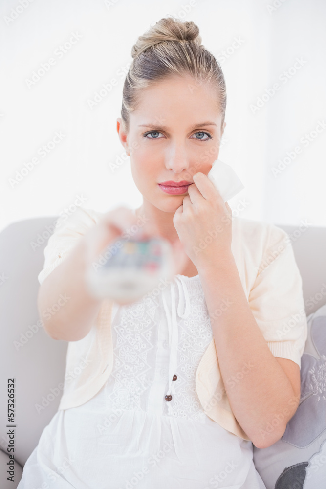 Anxious fresh model changing tv channel sitting on sofa Anxious fresh model changing tv channel sitting on sofa