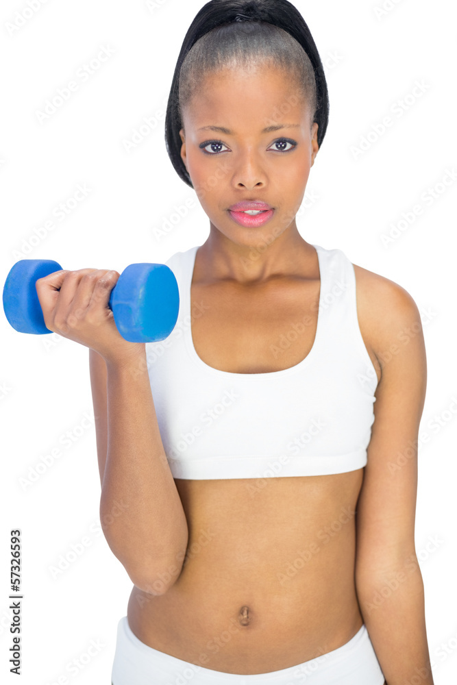 Serious woman in sportswear working out with dumbbell Serious woman in sportswear working out with dumbbell