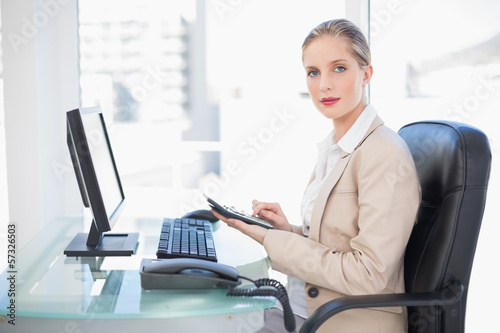 Side view of blonde businesswoman using calculator