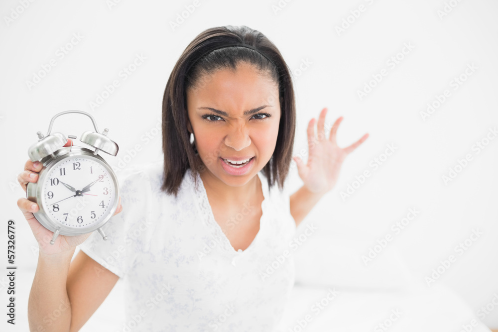 Furious young dark haired model throwing an alarm clock Furious young dark haired model throwing an alarm clock