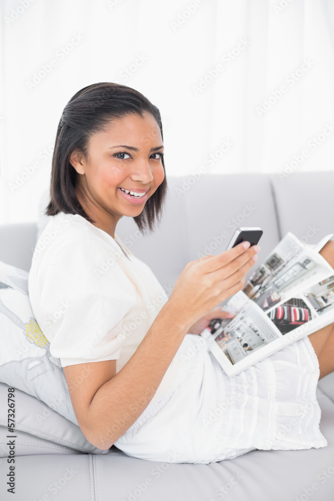 Smiling young dark haired woman in white clothes holding a magaz Smiling young dark haired woman in white clothes holding a magaz