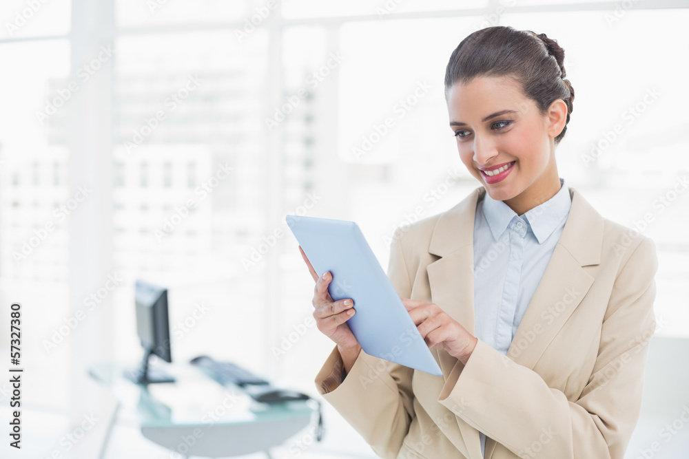 Pleased smart brown haired businesswoman using a tablet pc Pleased smart brown haired businesswoman using a tablet pc