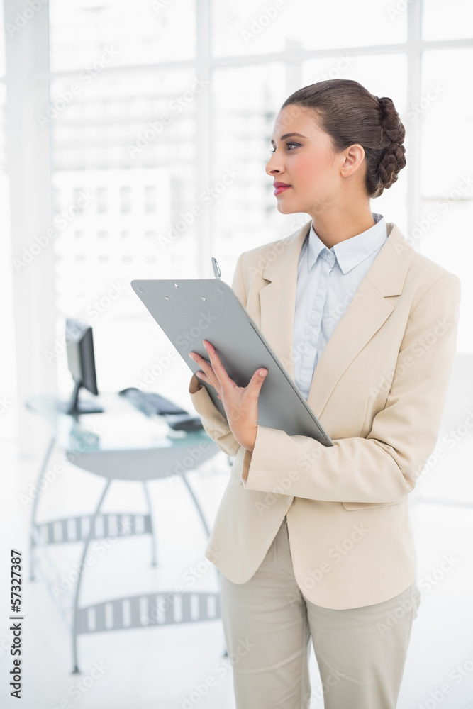 Thinking smart brown haired businesswoman checking a report Thinking smart brown haired businesswoman checking a report