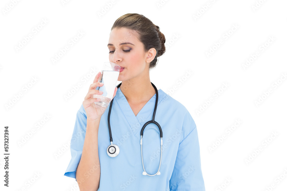 Peaceful brown haired nurse in blue scrubs drinking milk Peaceful brown haired nurse in blue scrubs drinking milk