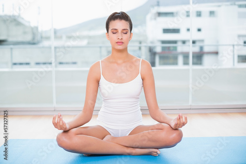 Peaceful natural brown haired woman in white sportswear practici