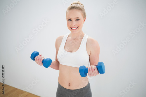 Cheerful sporty blonde holding dumbbells