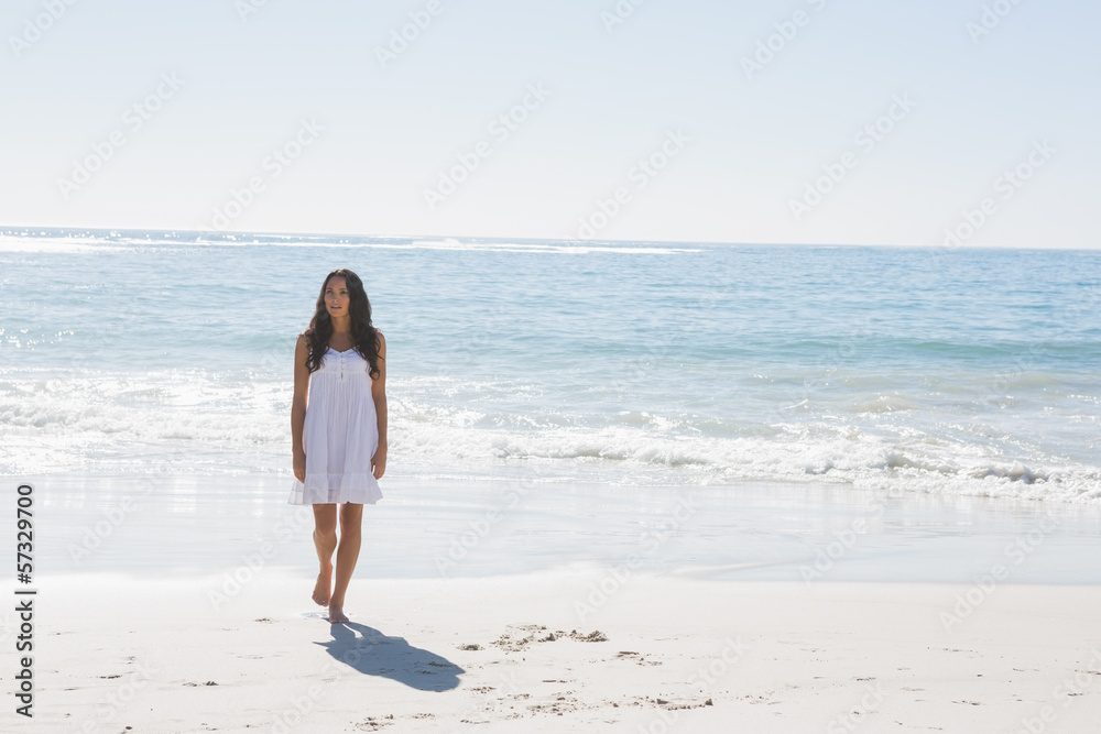 Brunette in white sun dress walking from the sea Brunette in white sun dress walking from the sea