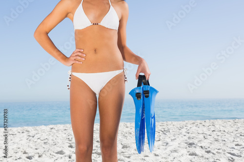 Sexy female body in white bikini holding fins