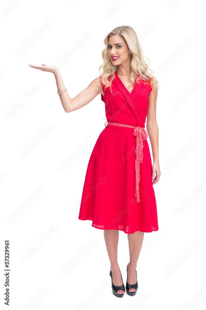 Cheerful woman in red dress presenting something in her hand Cheerful woman in red dress presenting something in her hand