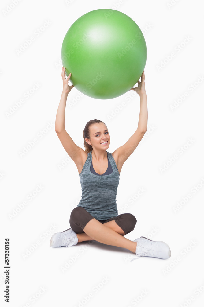 Sporty young woman lifting a green fitness ball Sporty young woman lifting a green fitness ball