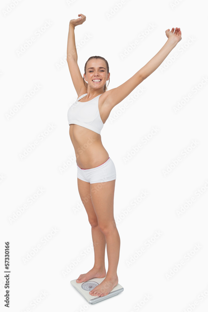 Happy slim woman standing on a scales spreading her arms