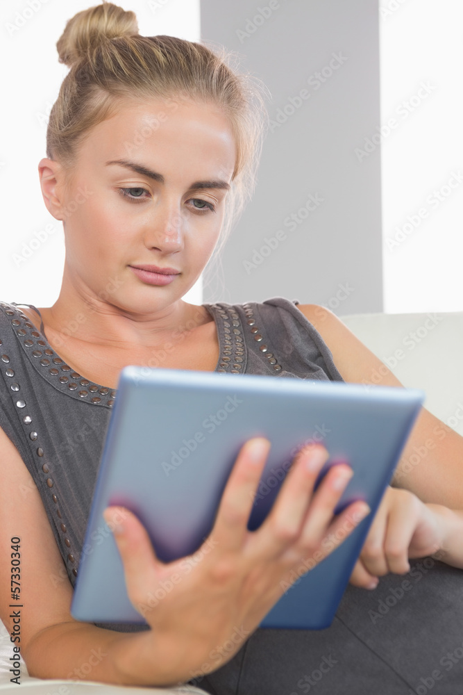 Fototapeta premium Casual serious blonde relaxing on couch using tablet