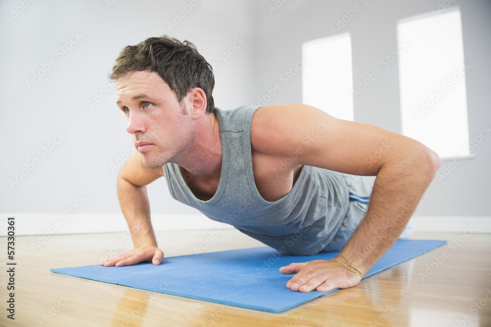 Attractive sporty man doing push ups on blue mat Attractive sporty man doing push ups on blue mat