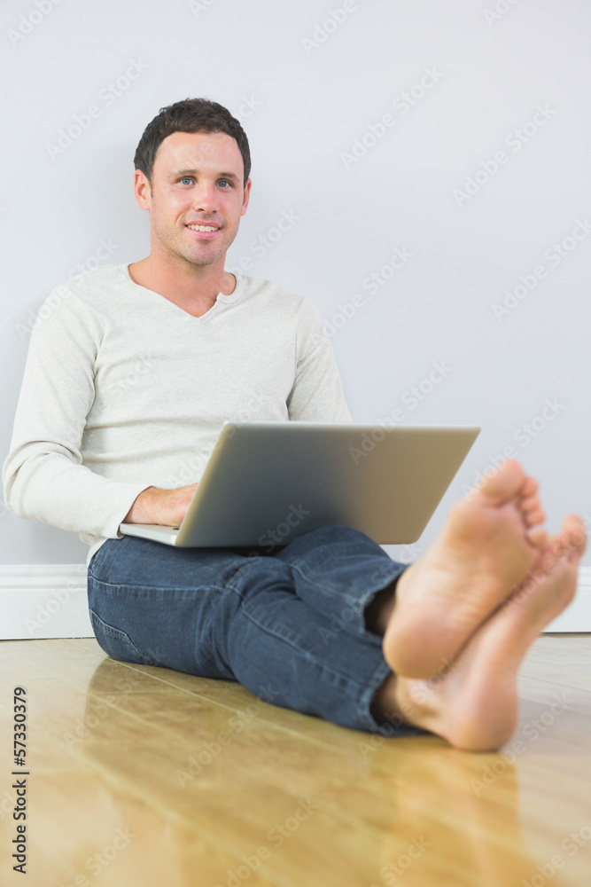 Casual lucky man leaning against wall using laptop Casual lucky man leaning against wall using laptop