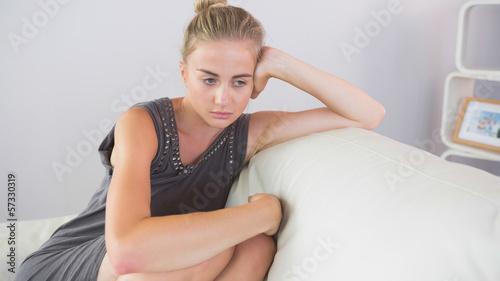 Casual worried blonde sitting on couch