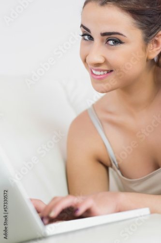 Beautiful woman smiling at the camera using her laptop