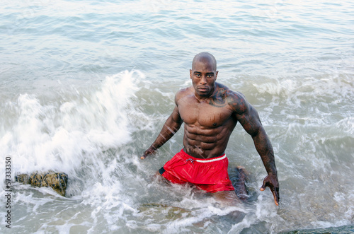 Strong bodybuilder fighting waves,working out with nature