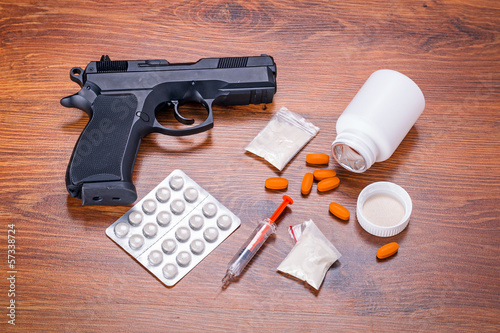 Set of narcotics and handgun on wooden table