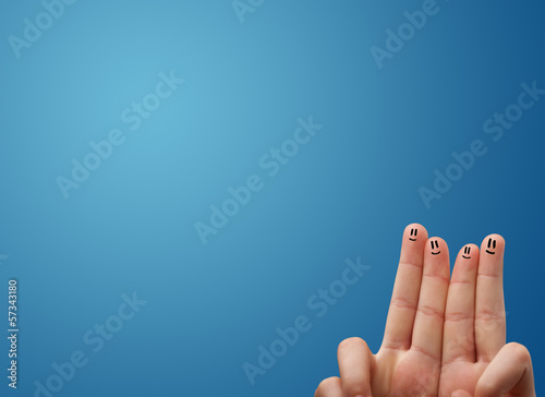 Happy smiley face fingers looking at empty blue background copy