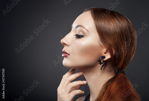beautiful young redhead woman isolated on dark background with c