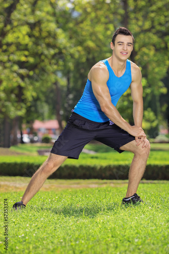 Young smiling sportsman exercising in a park