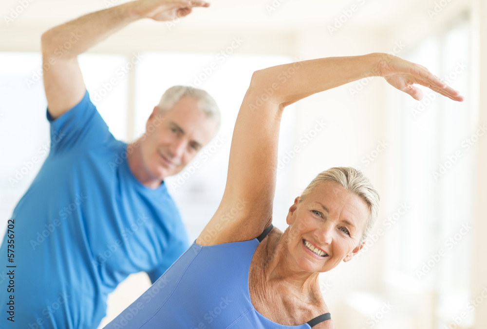 Fototapeta premium Couple Performing Stretching Exercise At Home
