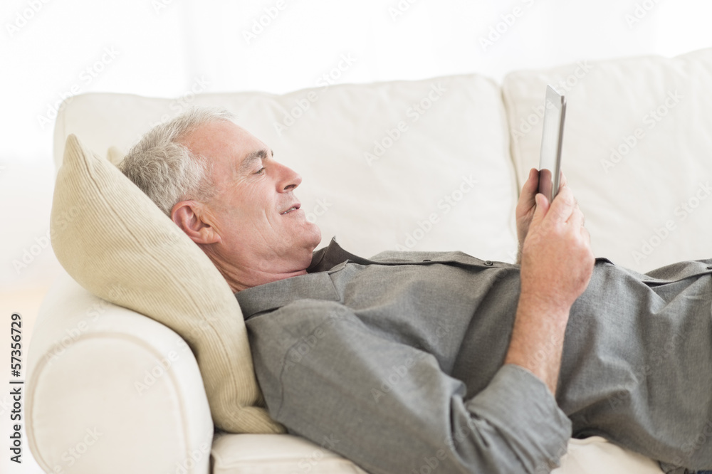 Man Using Digital Tablet On Sofa At Home Man Using Digital Tablet On Sofa At Home
