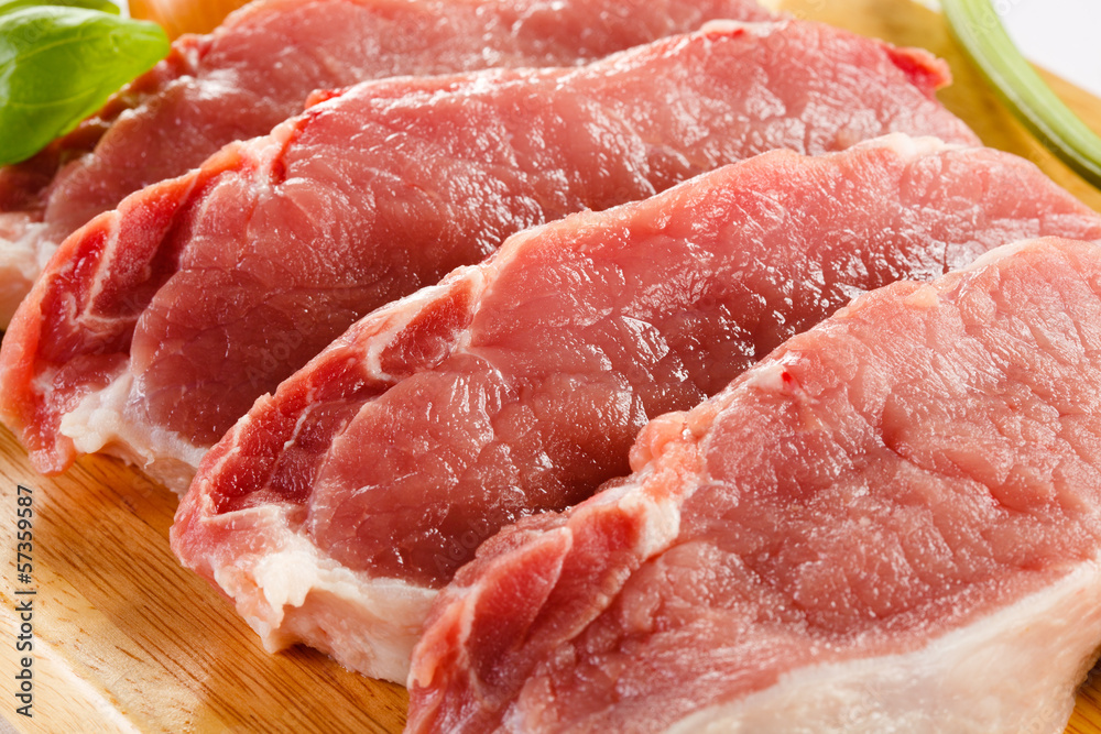 Raw pork on cutting board and vegetables