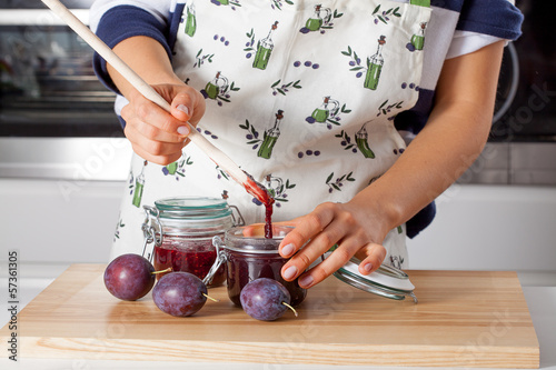 Housewife filling the jar with jam photo