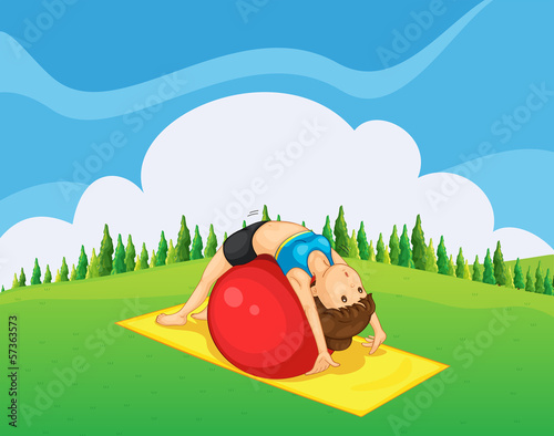 A young girl exercising with a bouncing ball at the hilltop
