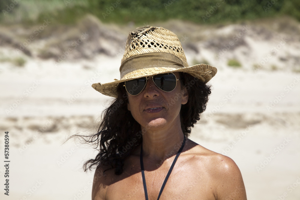 Mujer con sombrero de paja roto en la playa