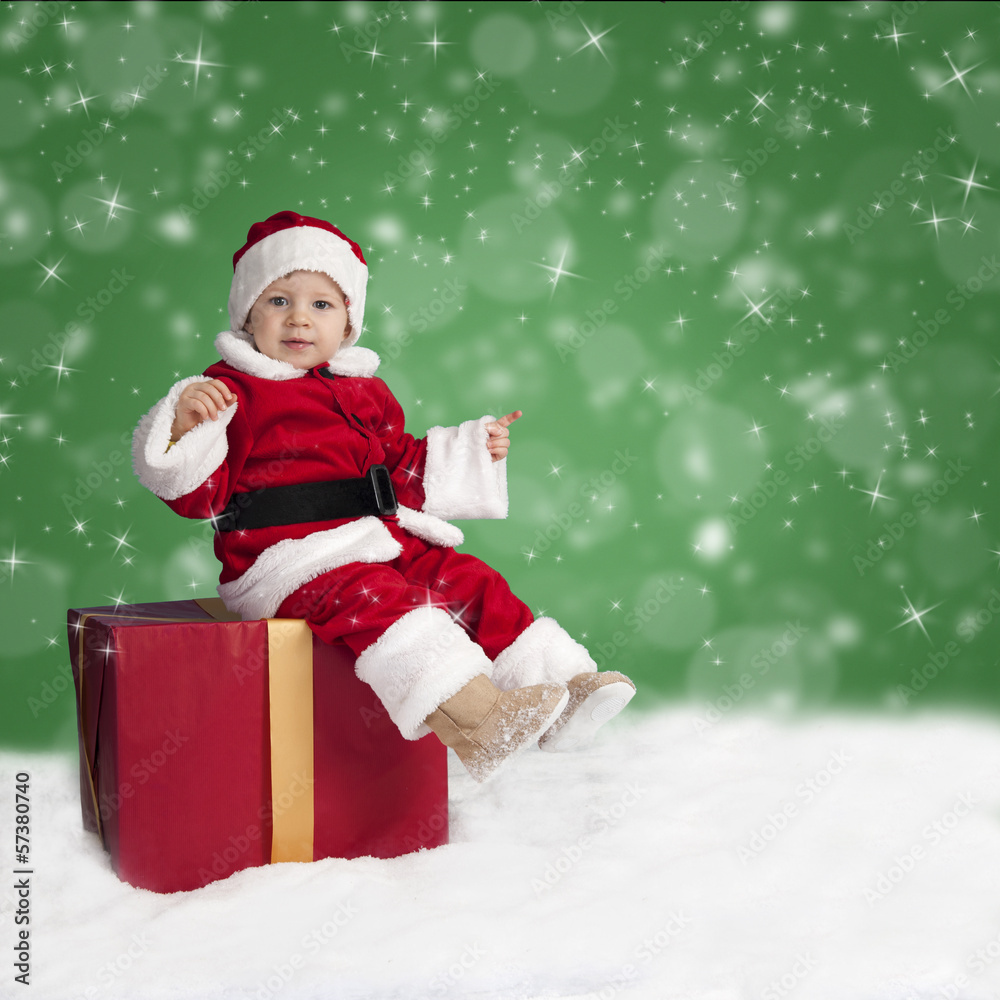 little santa claus seated on a Christmas present in the snow