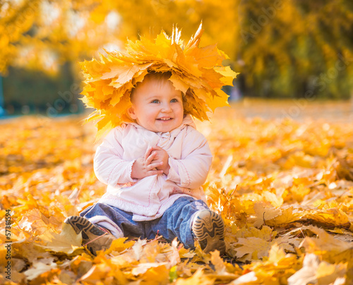 cute little girl among maple leaves