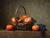 Still life with persimmons and grapes in a basket