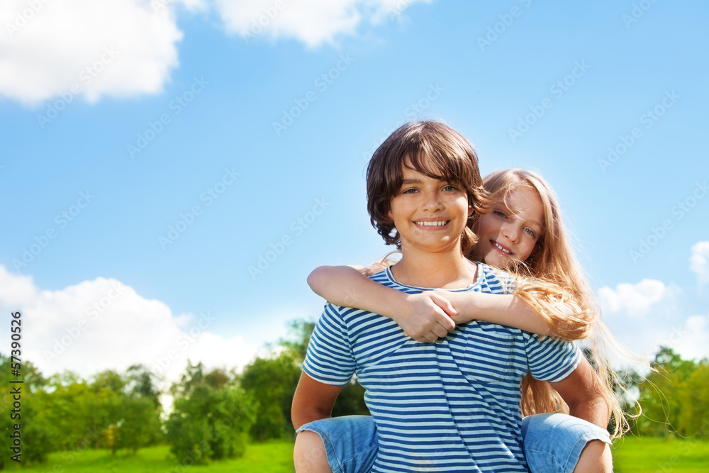 Happy couple of kids in the park with boy carry girl