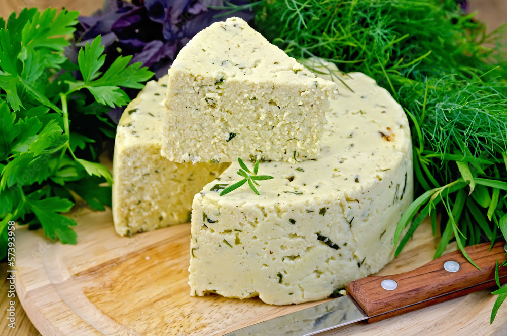 Cheese round homemade with herbs and knife on board