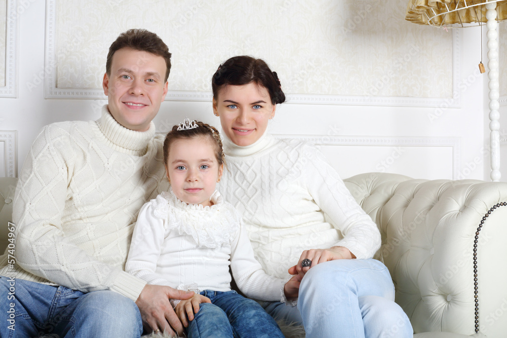 Father, daughter and mother in white sweaters and jeans sit Father, daughter and mother in white sweaters and jeans sit