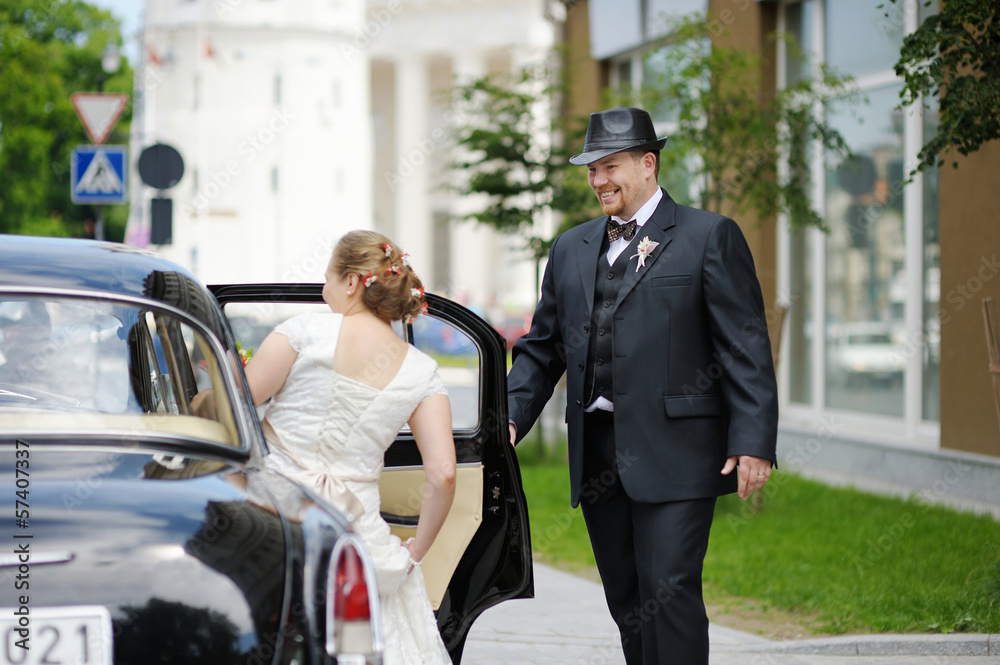 Groom helping his bride to get into a car